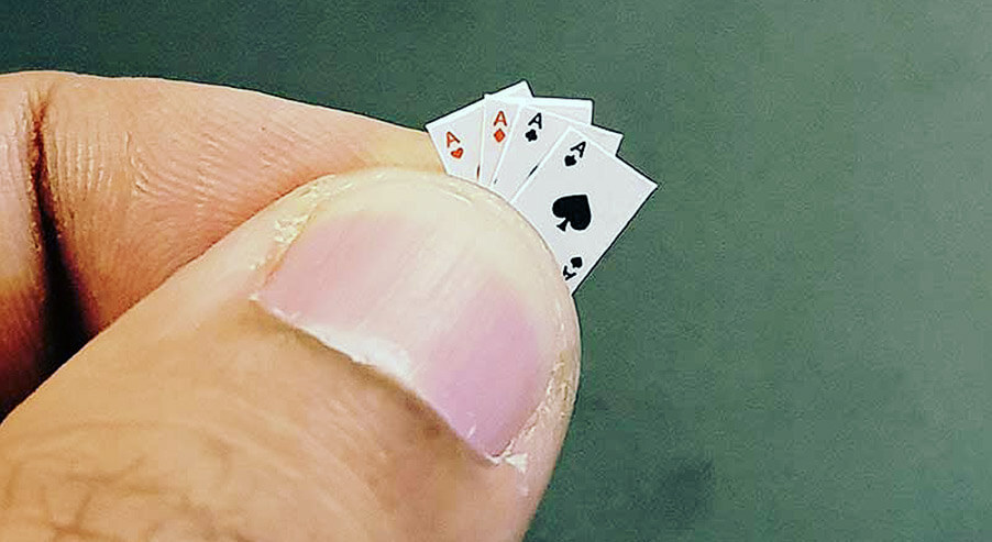 Two fingers holding the smallest playing cards in the world